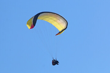 Tandem Paraglider flying in a blue sky	