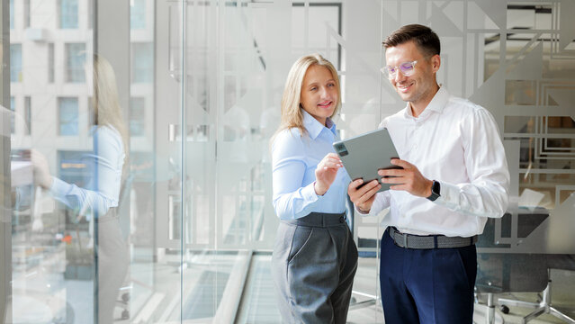 Business professionals engaged in discussion while using a tablet in a modern office interior