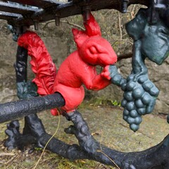 Close-up of red squirrel decorative metalwork on an old iron bench outdoors.