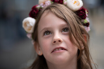 Close-up portrait of a smiling Ukrainian girl in an embroidered blouse and floral wreath looking up, concept of childhood joy and Ukrainian tradition.