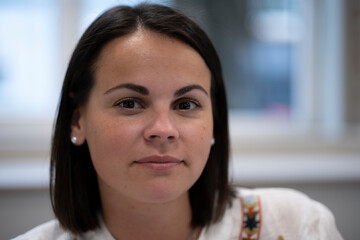 Close-up portrait of a dark-haired brown-eyed young woman indoors with copy space on the side, concept of beauty and natural elegance