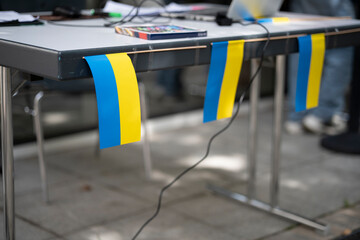 Three small Ukrainian flags attached to a table at an event dedicated to Ukraine, concept of national pride and unity.