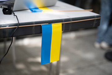 Single small Ukrainian flag attached to a table at an event dedicated to Ukraine, concept of national pride and unity.