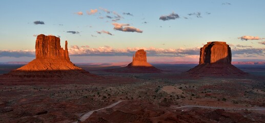 Landscape of Monument Valley in Arizona at sunset, showing the East Mitten Butte, West Mitten Butte, and the Merrick Butte