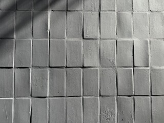 Gray tiles creates a minimalist, modern backdrop on the wall. The repeating grid conveys structure, texture, and a quiet industrial mood suitable for architecture, design, and urban visuals.
