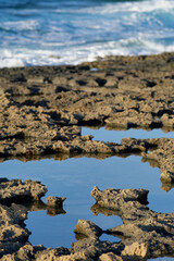 Coastal rock formations with tidal pools reflecting blue sky in Crete Greece