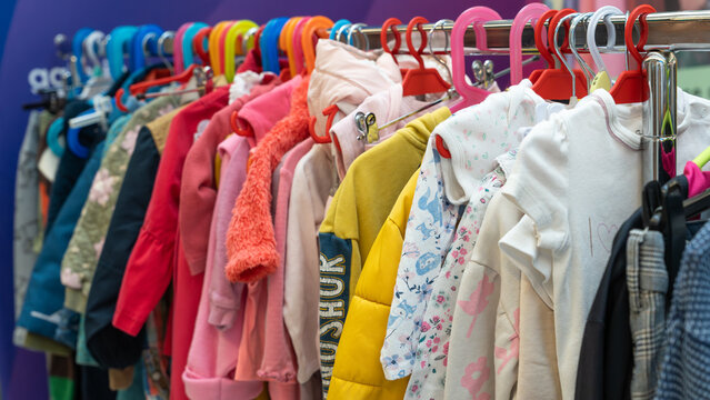 Colorful children's clothes hanging on a rack at a sustainable swap event. Various jackets, sweaters, and shirts in bright colors symbolize reuse, recycling, and eco-friendly fashion for kids. - Powered by Adobe