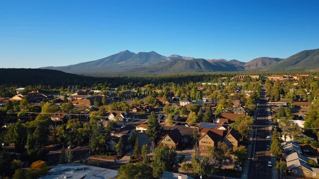 Flying over the green cityscape of Flagstaff, Arizona, USA. Beautiful lush woods and mountains at backdrop.