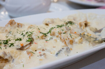 Chicken fillet with mushrooms in creamy sauce served on a white plate at a festive dining table.