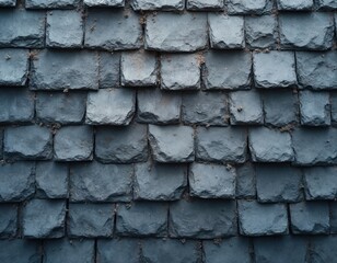Slate roof tiles form a repeating pattern on an exterior surface. The gray stone material provides durable weather protection for a home roof.
