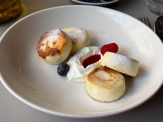 Cheesecakes with berries and cream on white plate. Dessert harmony, delicate sweetness, and cozy cafe indulgence.