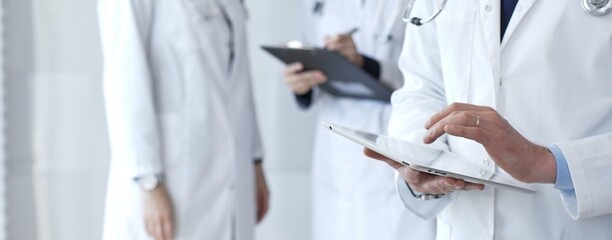 Healthcare professional using a digital tablet for patient data management, doctors collaborating on medical records, modern clinic team focusing on health technology