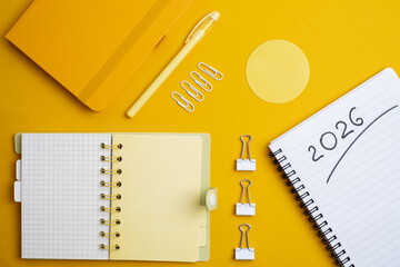 Happy New Year 2026 and a notepad on a colored background. Layout for writing annual business plans, schedules, as well as New Year's resolutions and goals. 