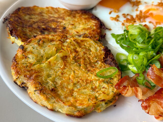Potato pancakes with sour cream and onion on plate. Traditional meal, homemade flavor, and cozy rustic breakfast.