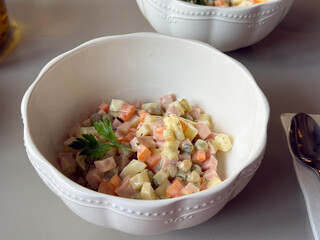 Close-up of Olivier salad with diced vegetables and ham. Homemade cooking, family celebration and comfort through traditional festive food.