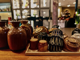 Authentic handcrafted Japanese pottery and cups arranged on a wooden counter under soft indoor lighting — ideal for themes of craftsmanship, dining, or Japanese culture.