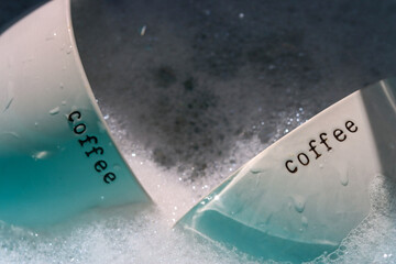 Two empty coffee cups in soapy water waiting to be washed. 