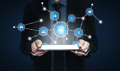 A businessman holds a tablet displaying digital icons connected by lines, symbolizing innovation, connectivity, and modern technology in a secure environment. Tessel