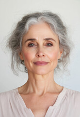 Portrait of a mature woman with gray hair and a serene expression against a neutral background