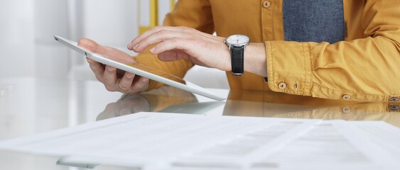 Person using a digital tablet for business at desk, navigating online content or browsing...