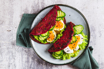 Close up of beet chia tacos with egg, cucumber and lettuce on a plate on the table top view