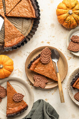 Traditional pumpkin pie with chocolate crust and leaf shaped decorations with a slice taken out. Seasonal autumn Thanksgiving food top view
