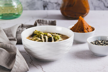 Delicious miso soup with noodles and broccoli in a bowl on the table