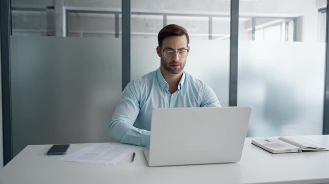 Young manager businessman specialist doing paperwork analysing on pc. Focused latin business man salesman working on laptop computer reading financial contract report document in office workplace. 