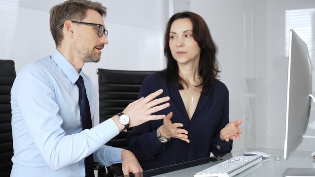 Business professional colleagues or partners collaborating and communicating on a desktop computer, analyzing information, sharing insights, and developing strategies in a modern office environment