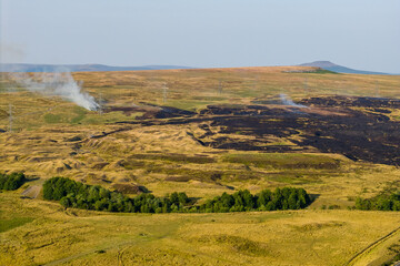 Burnt, blackened landscape after a wildfire on dry moorland in the Welsh countryside