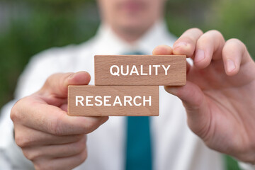 Business person holding wooden blocks sees the words QUALITY RESEARCH. Inspect Quality Research Review Business Concept. Quality Certificate Assessment.