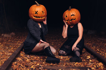 Two friends celebrating Halloween with pumpkin heads on a serene autumn night in a forest setting