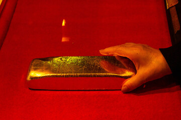 赤い絨毯に置かれた金塊を持ち去ろうとする