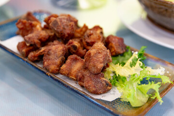 Crispy fried pork ribs served on rectangular ceramic plate with fresh lettuce garnish, golden brown coating indicating deep fried traditional Cantonese style