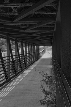 Passarela fotografada em preto e branco, destacando linhas, formas e texturas da estrutura. Composi&ccedil;&atilde;o minimalista que real&ccedil;a perspectiva, contrastes de luz e sombra, criando atmosfera atemporal e art