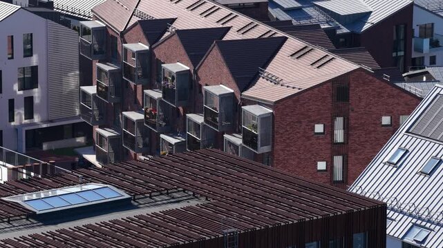 Contemporary brick residential architecture in Vilnius, Lithuania, featuring uniform gable roofs and cube-shaped cantilevered balconies with vertical railing screens.