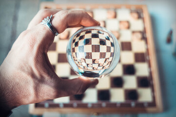 Hand Holding Lensball Reflecting Checkers Board Game Upside Down for Strategy Concept