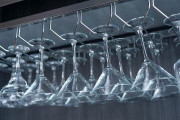 Elegant row of martini glasses hanging upside down in bar. Soft focus