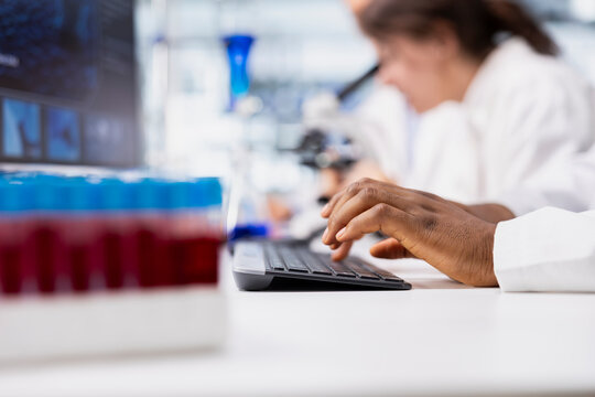 Close up of laboratory researcher using computer software to process DNA patient data for clinical research. Lab specialist typing on PC keyboard, doing genetic analysis diagnostics