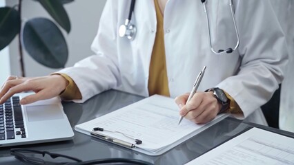 Doctor woman is working on laptop with medical reports. Healthcare professional reviews patient files and inputs data in a clinic setting. Medicine