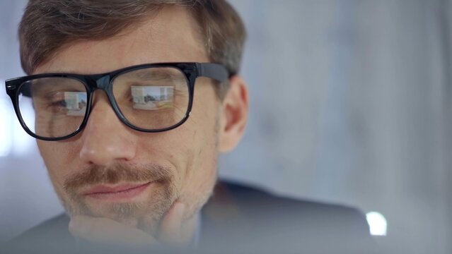 Businessman with glasses looking intently obscured partially by a translucent surface of laptop. Business concept
