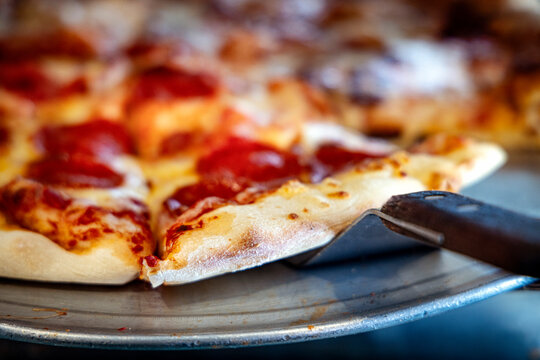 Close up of the cust of a pepperoni and cheese pizza for purchase by the slice in a glass display