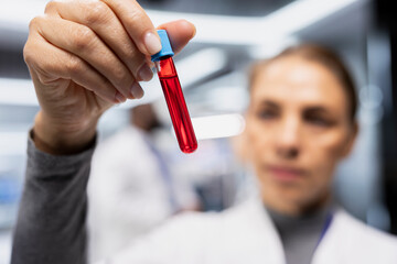 Woman scientist collecting and checking blood in test tubes during drug test, doing a medical study to obtain new vaccine in laboratory. Biotechnology data for healthcare progress.