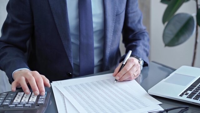 Businessman analyzing financial data on laptop and calculator. Close-up of a professional auditor working on financial reports. Business concept