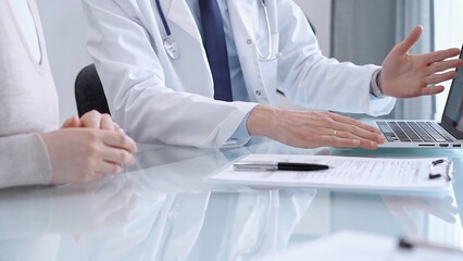 Doctor is consulting patient in modern fair clinic. Healthcare professional discusses medical...