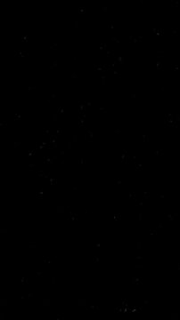 Smartphone-ratio stop-motion dark retro film grain texture with dust and scratches on a black background, ideal for video overlays or aged photo effects.