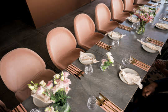 Elegant table setting with blush pink velvet chairs, floral centerpiece, and gold cutlery arranged for a luxury event or fine dining experience