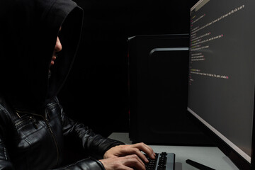 a hooded hacker man writing an html code into a computer in a crimila atmosphere