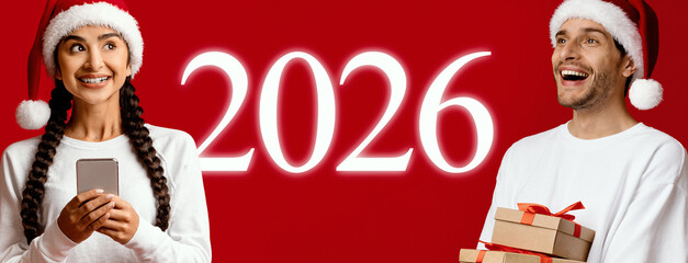 Two happy individuals dressed in holiday attire are surrounded by festive elements. They hold gifts and a phone, embodying the spirit of Christmas and excitement for the upcoming year, 2026.