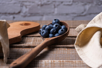 Wooden ladle filled with blueberries and copy space.